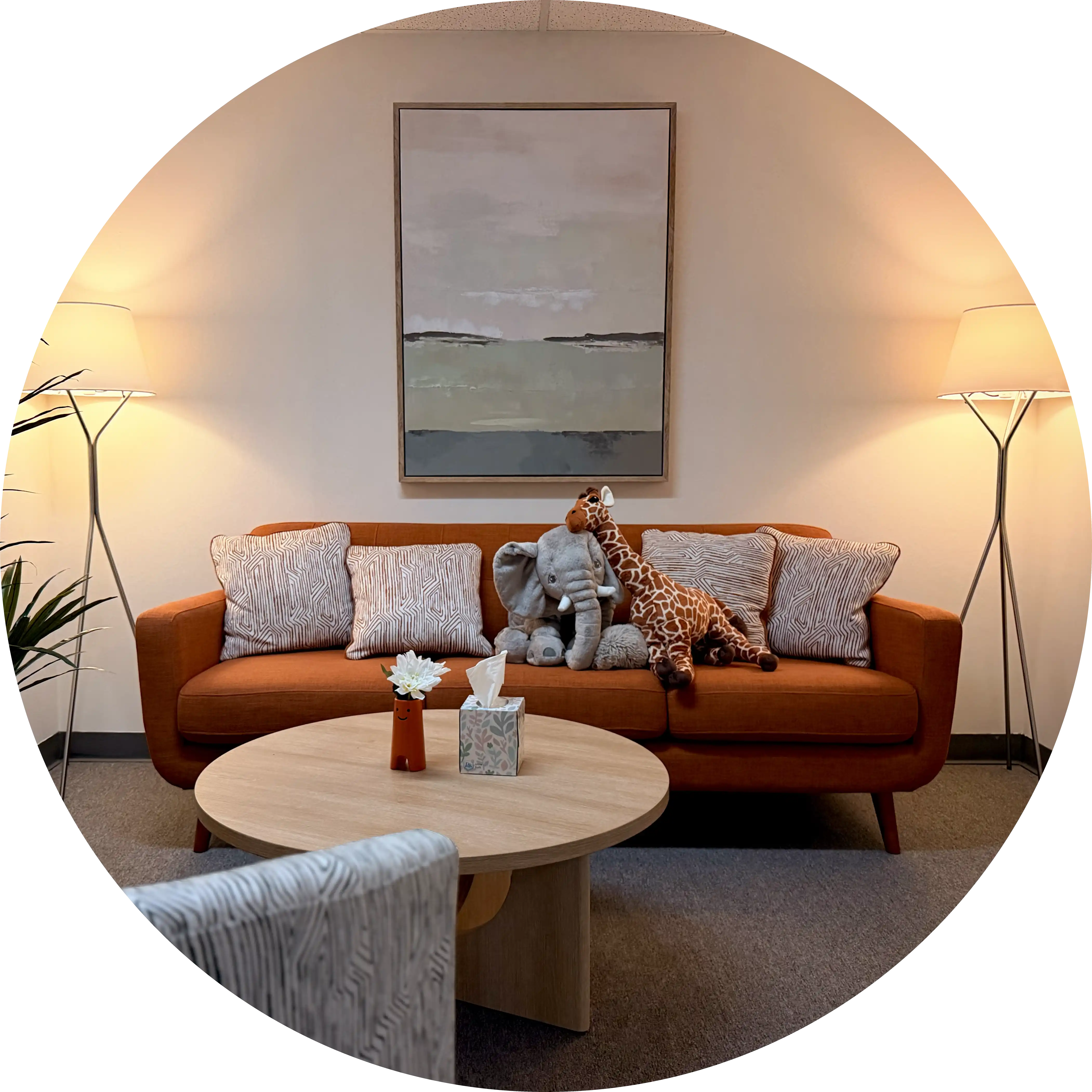 One of the therapy rooms at Behavioral Aid Solutions: an orange sofa with plush toys, two floor lamps, and a round coffee table