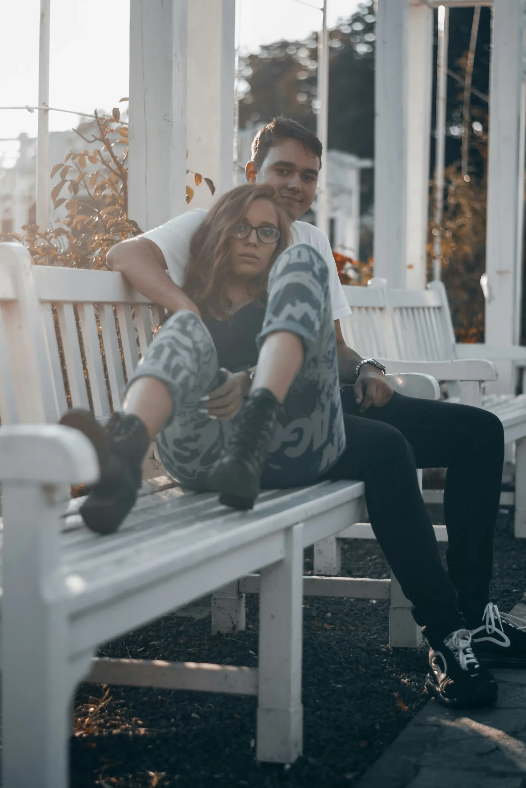 A couple sitting closely together on a bench outdoors