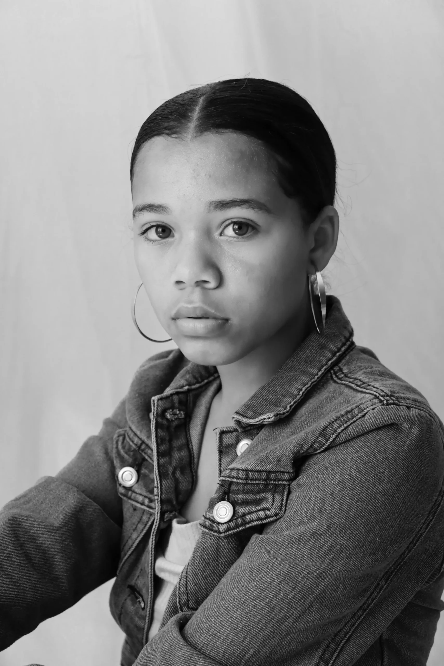 A black-and-white portrait of a teen girl with a serious, direct gaze
