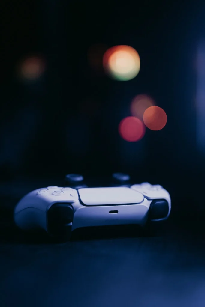 A video game controller resting alone on a table in a dark room, with blurred city lights in the background