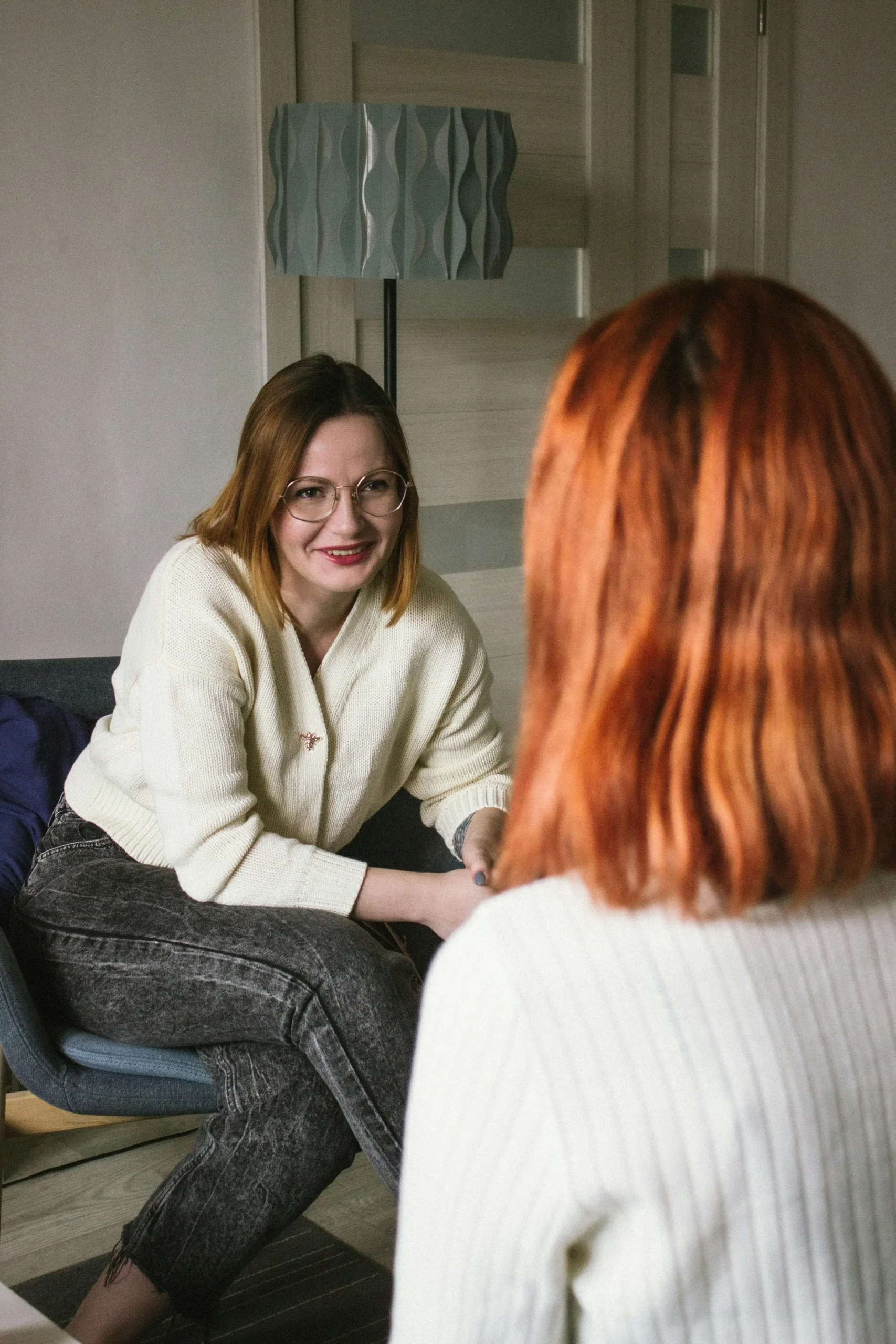 A therapist smiling warmly while holding her client's hand during a session