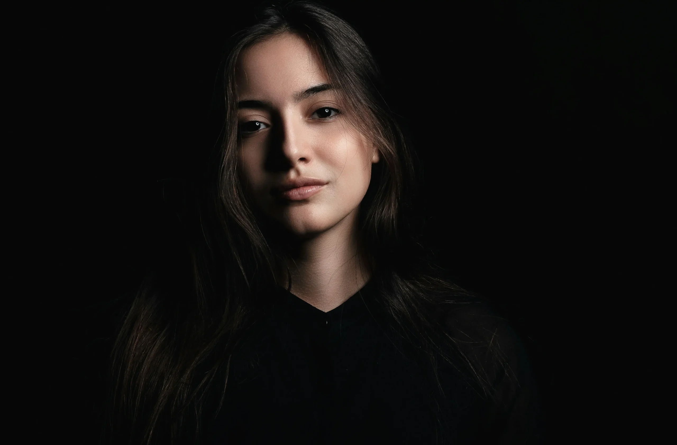 A moody, low-lit portrait of a teen girl looking off to the side