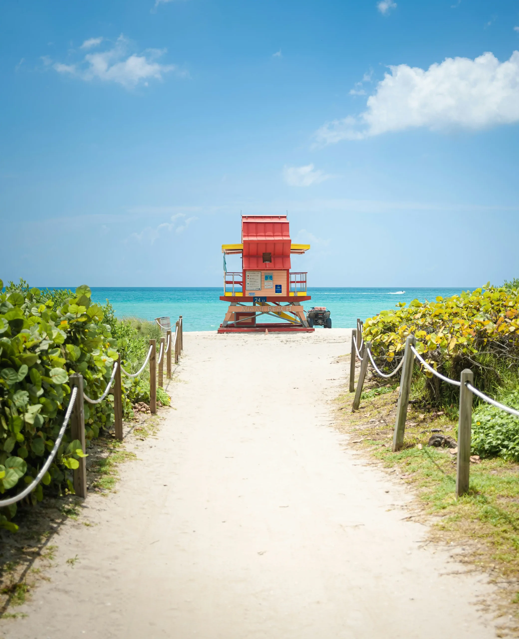 A colorful red and yellow lifeguard stand on Miami Beach at the end of a sandy path