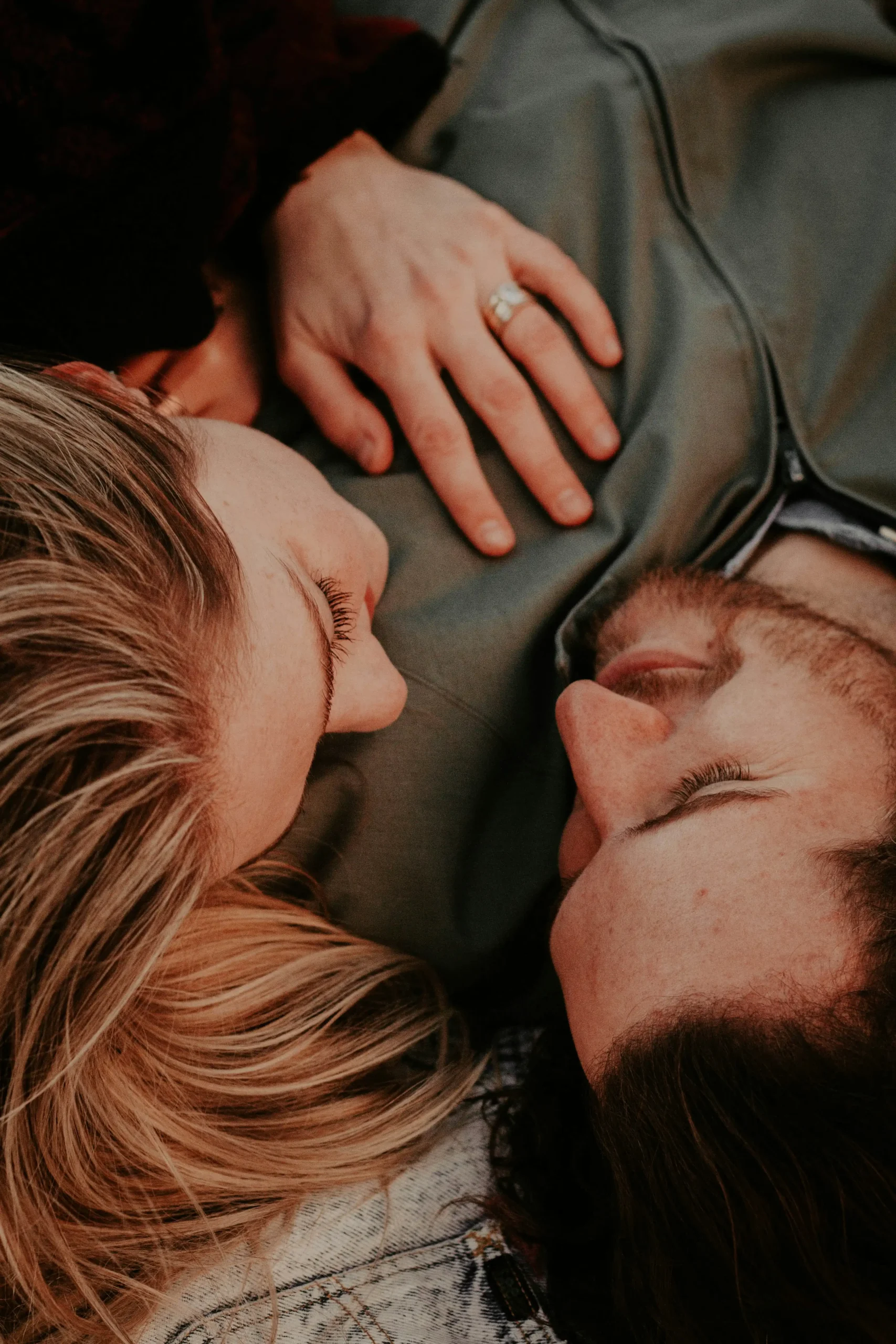 A couple lying close together, foreheads nearly touching, her hand resting on his chest