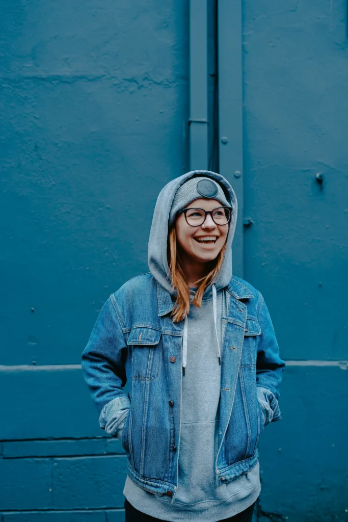 A teen girl laughing warmly in a hoodie and denim jacket