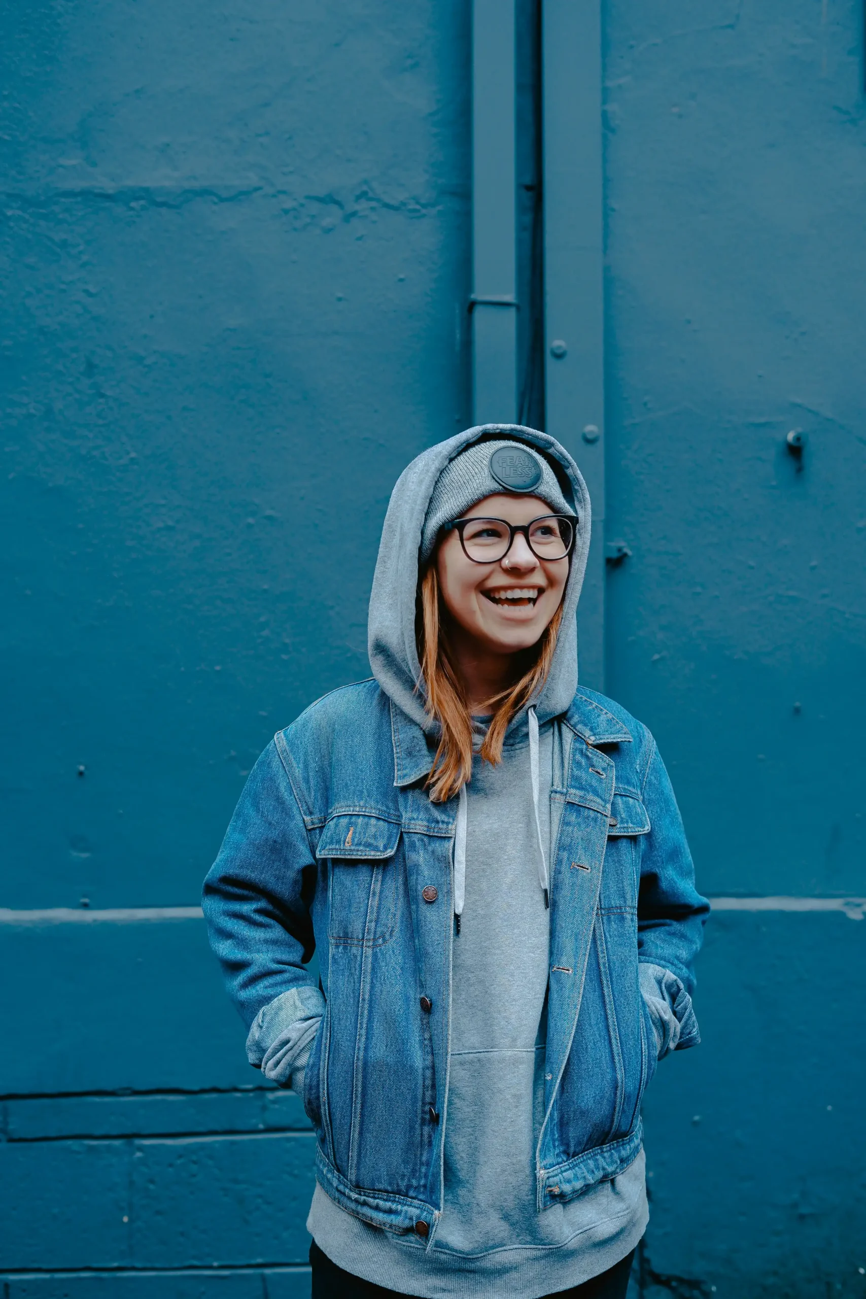 A teen girl laughing warmly in a hoodie and denim jacket