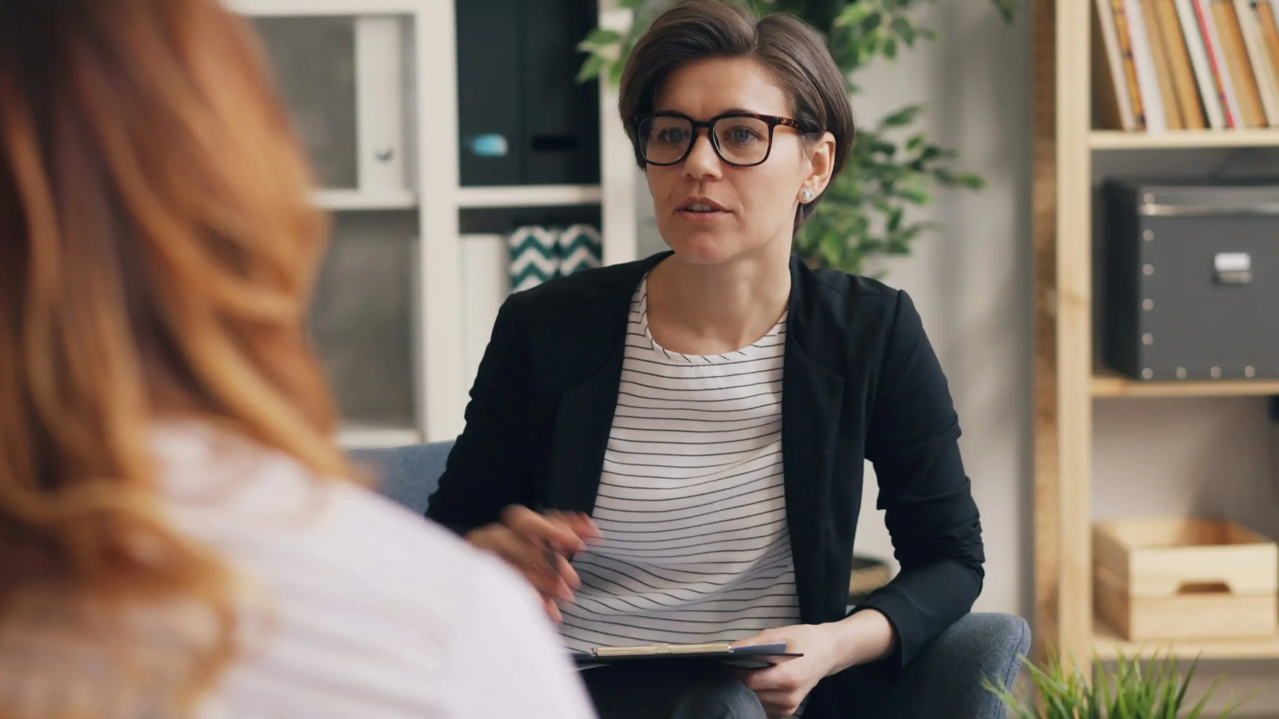A therapist talking with a client in a warm, book-lined office