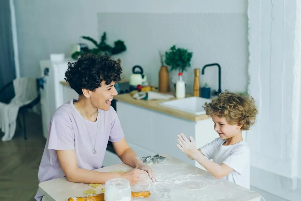 Una mujer y un niño riendo juntos en una cocina luminosa